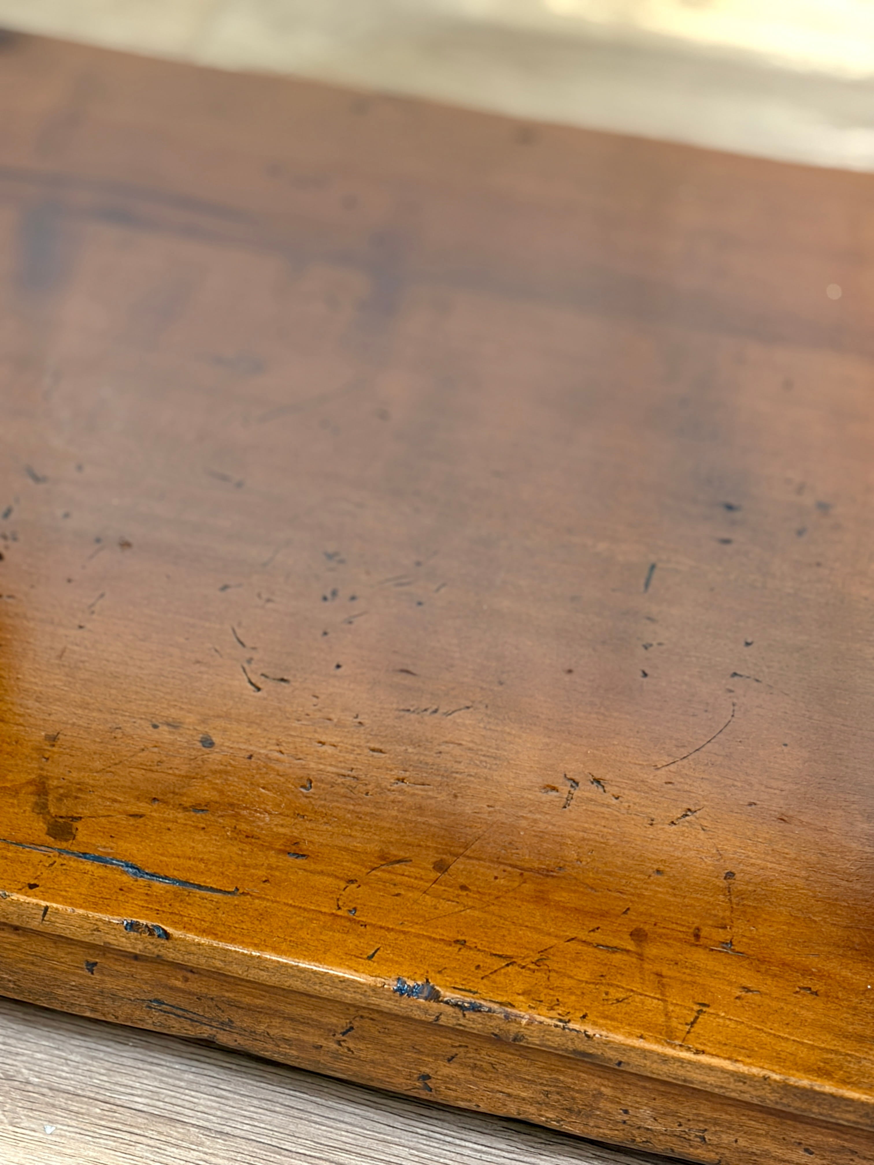 Close-up of a worn wooden surface with visible scratches and scuffs.