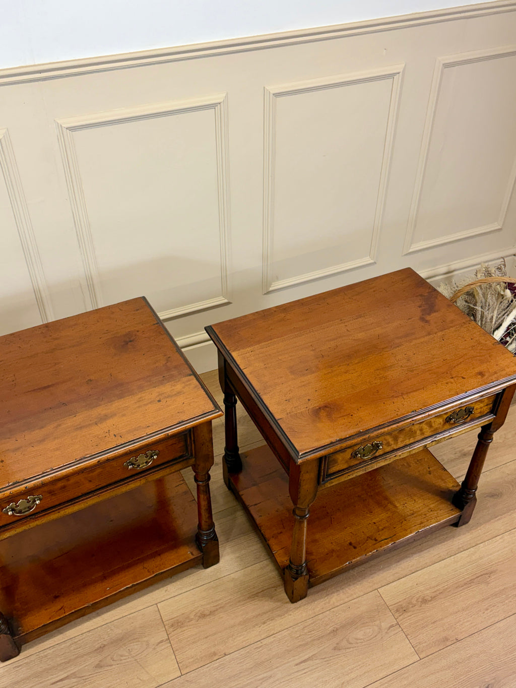 Two wooden side tables against a paneled wall.