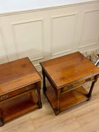 Two wooden side tables against a paneled wall.