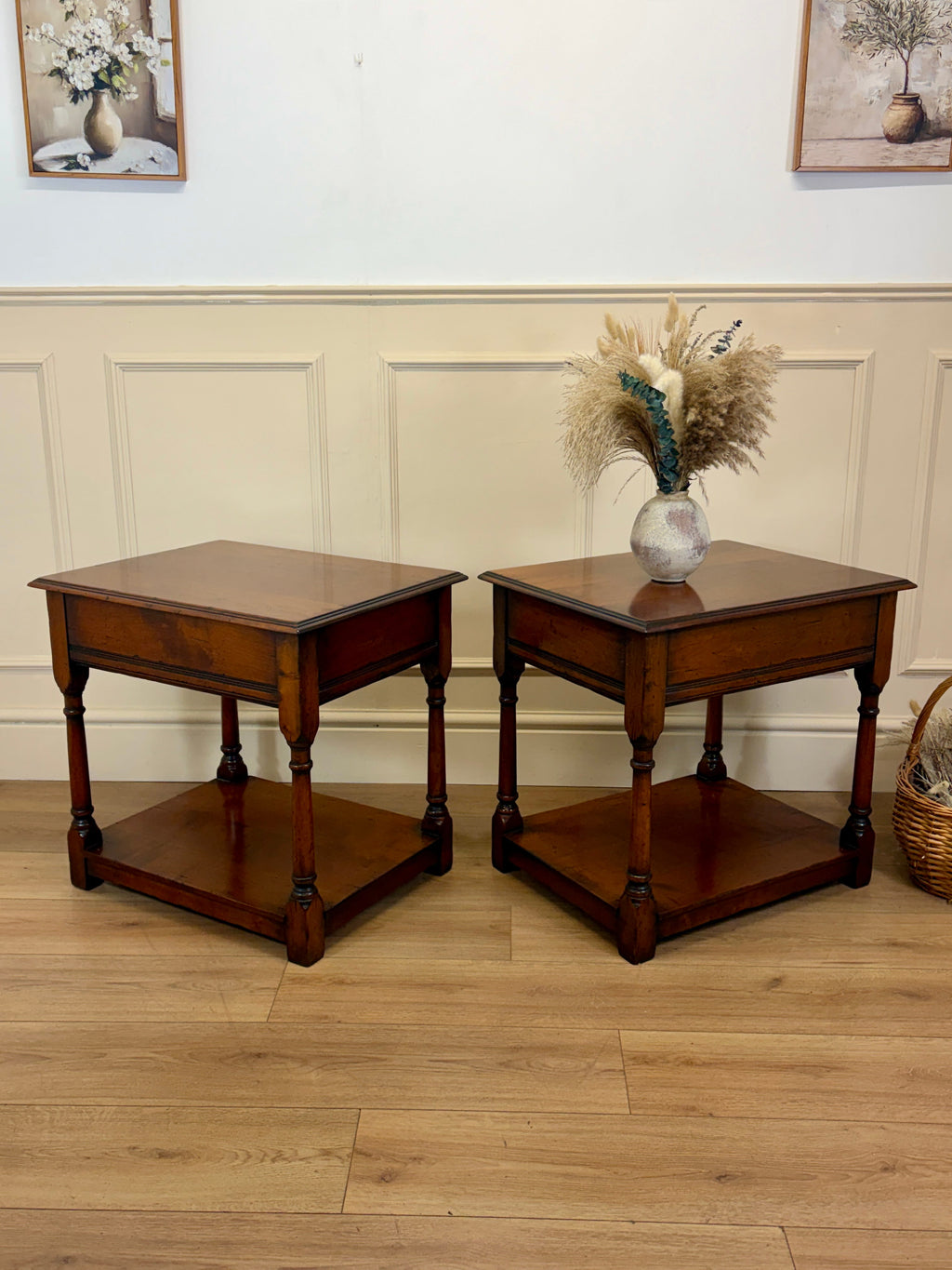 Two wooden side tables with a vase of flowers on a wooden floor.