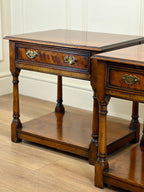 Pair of wooden side tables with drawers on a wooden floor.