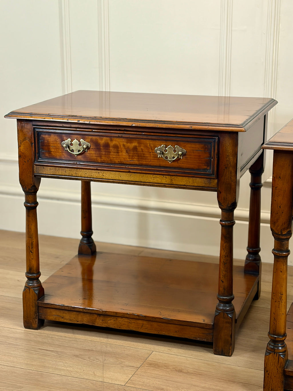 Wooden side table with a drawer on a wooden floor.