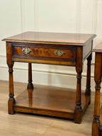 Wooden side table with a drawer on a wooden floor.