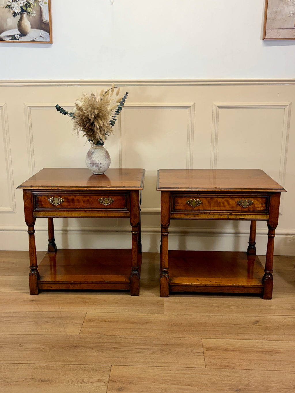 Two wooden side tables with a vase of flowers on a light wood floor.