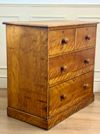 Wooden dresser with four drawers on a wooden floor.