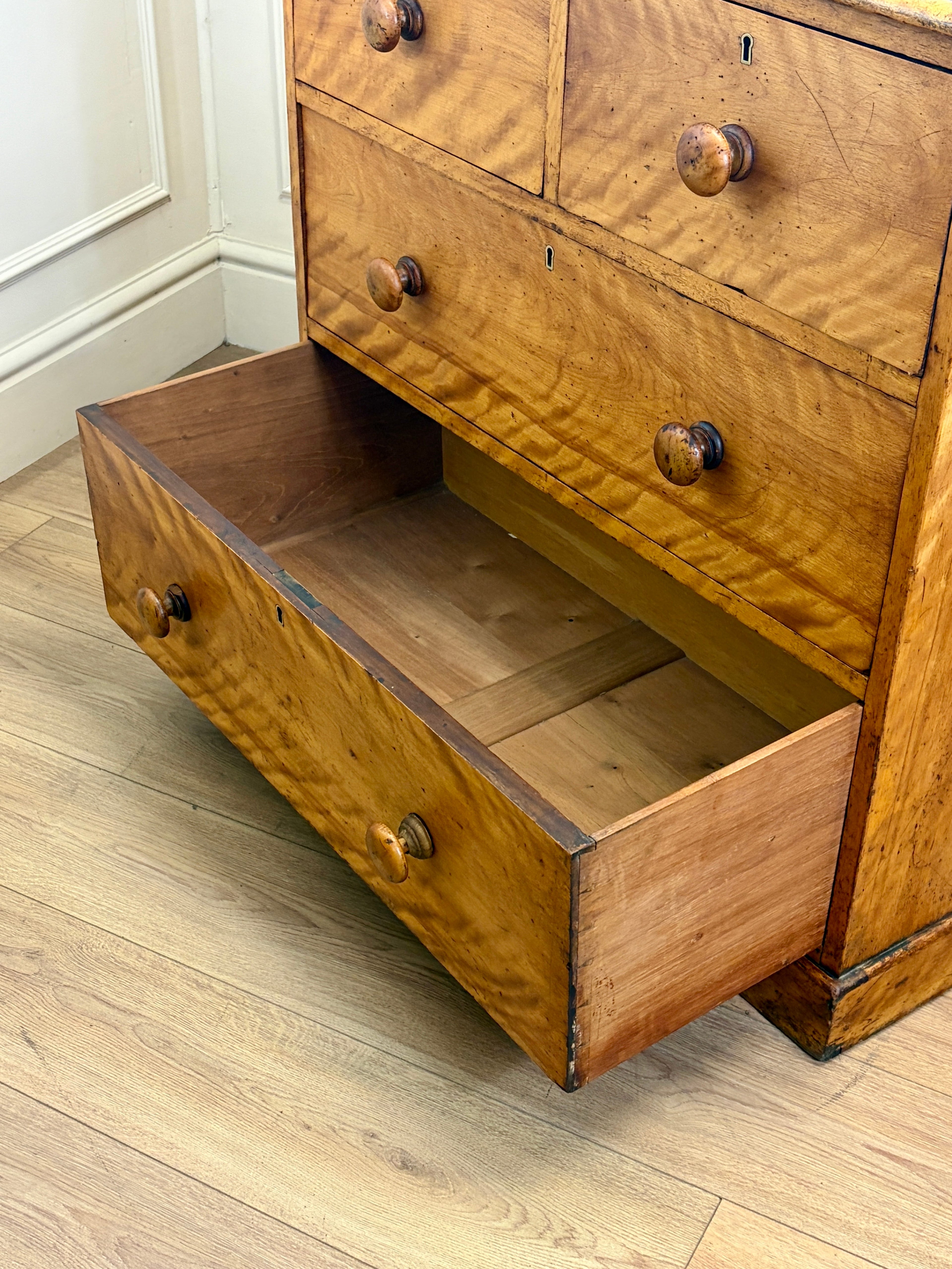 Wooden dresser with open drawer on a wooden floor