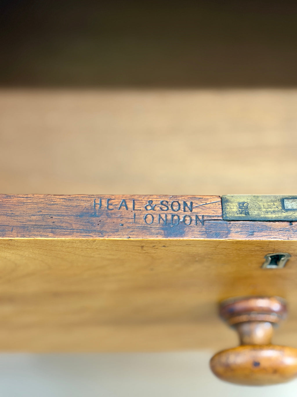 Wooden object with 'Heal & Son London' branding on a blurred background
