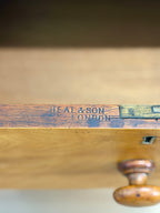 Wooden object with 'Heal & Son London' branding on a blurred background