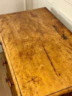 Vintage wooden desk with a worn surface in a room with white walls.