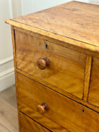 Wooden dresser with two drawers and a knob on a white wall background