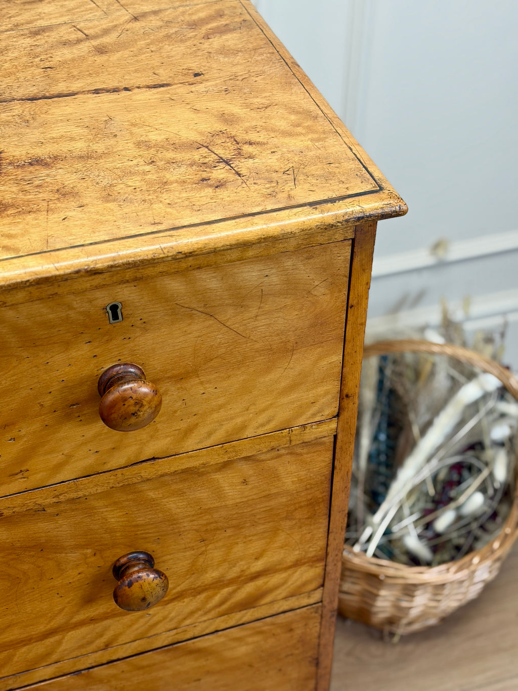 Wooden dresser with two drawers and a basket in the background