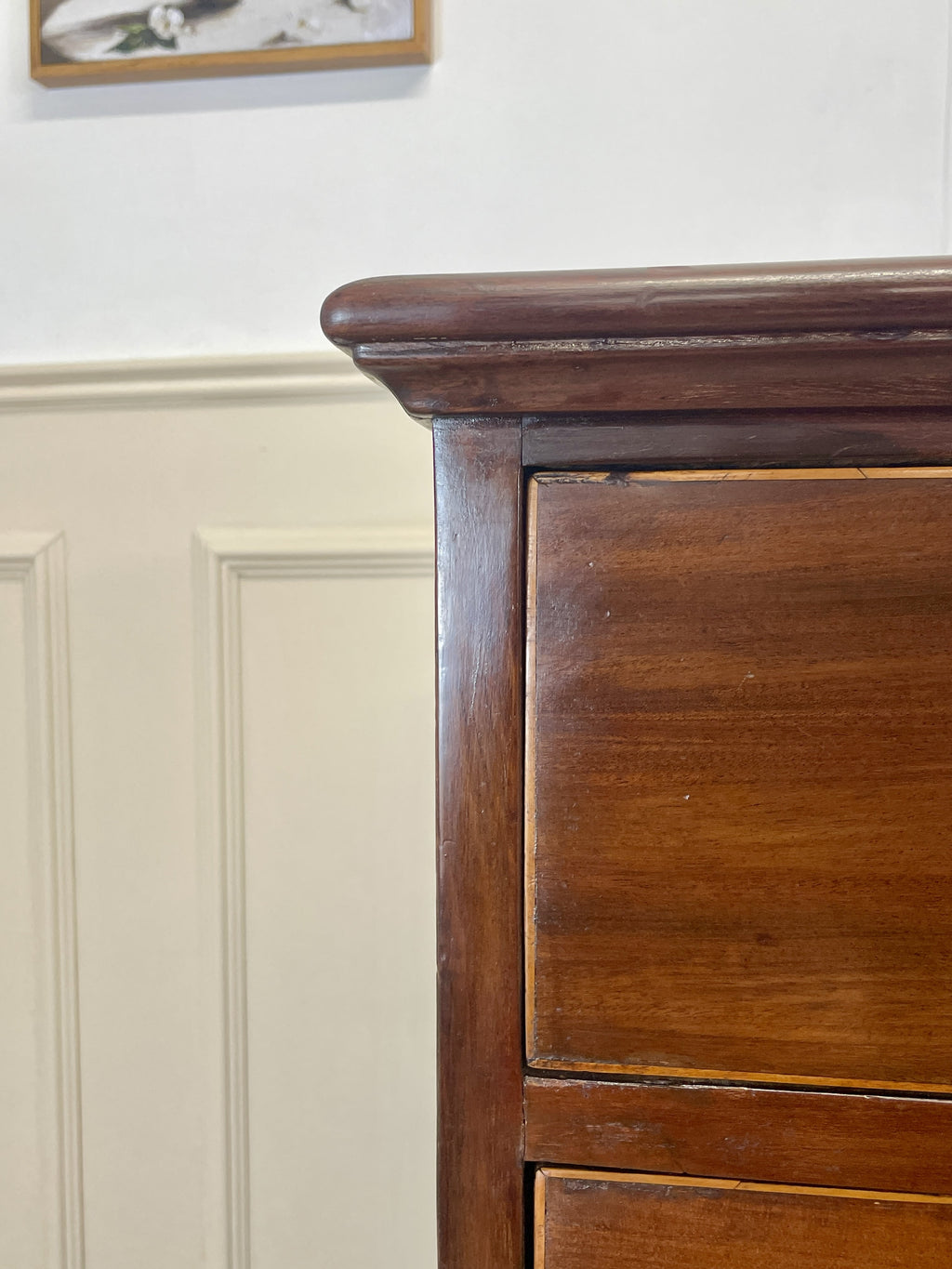 Close-up of a wooden dresser with paneling in the background
