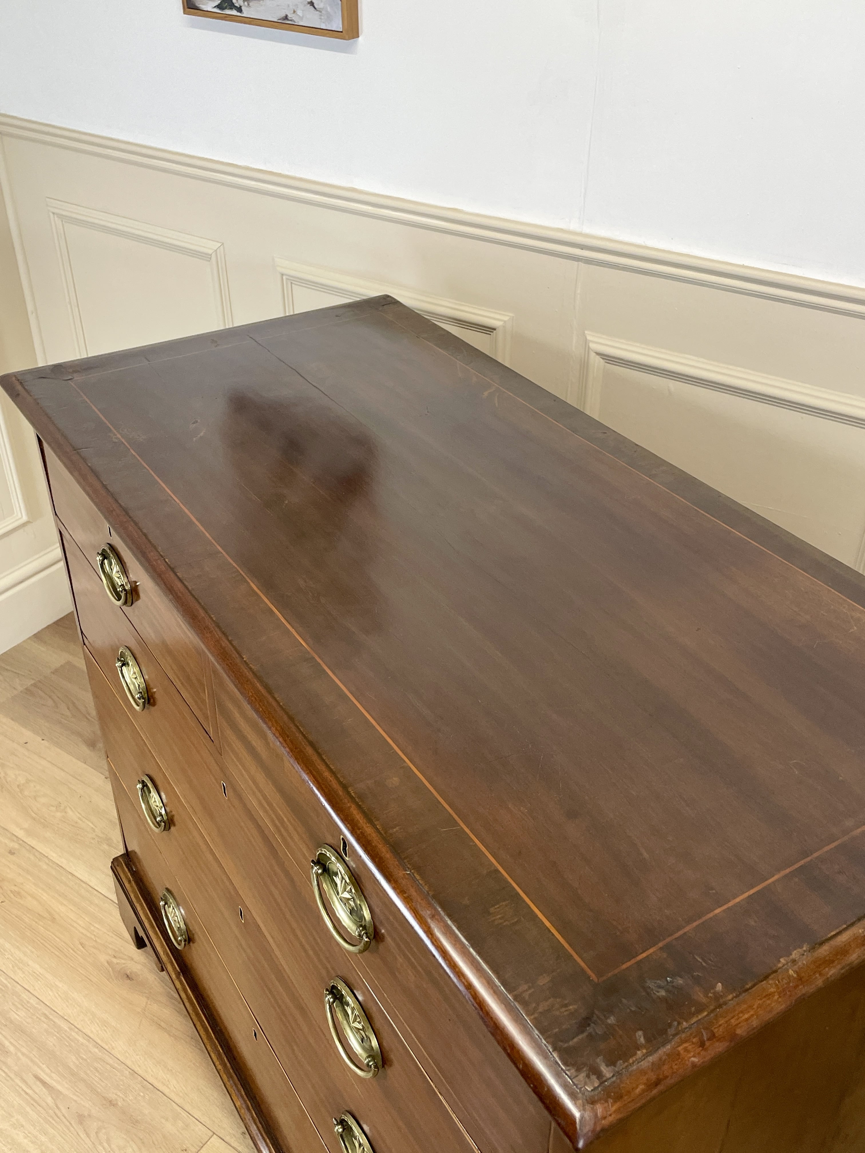 Wooden dresser with brass handles in a room with white walls and wooden floor.