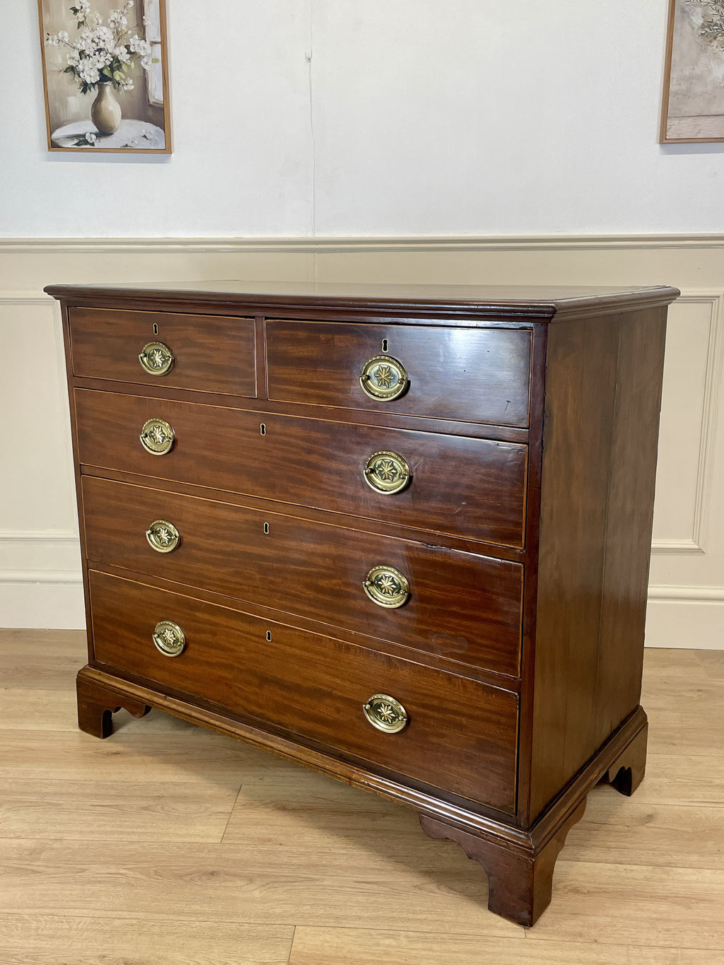 Wooden dresser with brass handles on a wooden floor.
