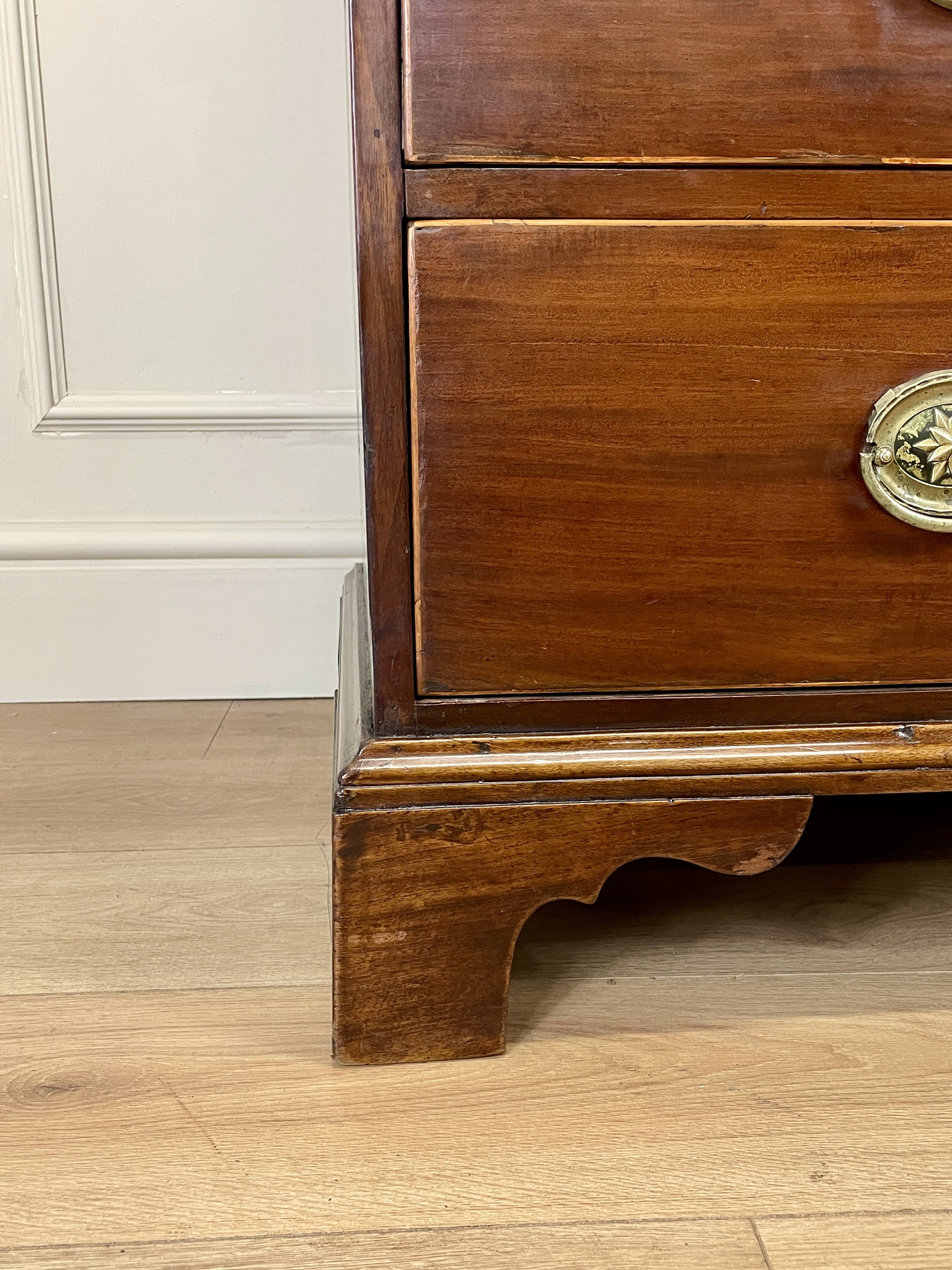 Wooden drawer with brass handle on a wooden floor.