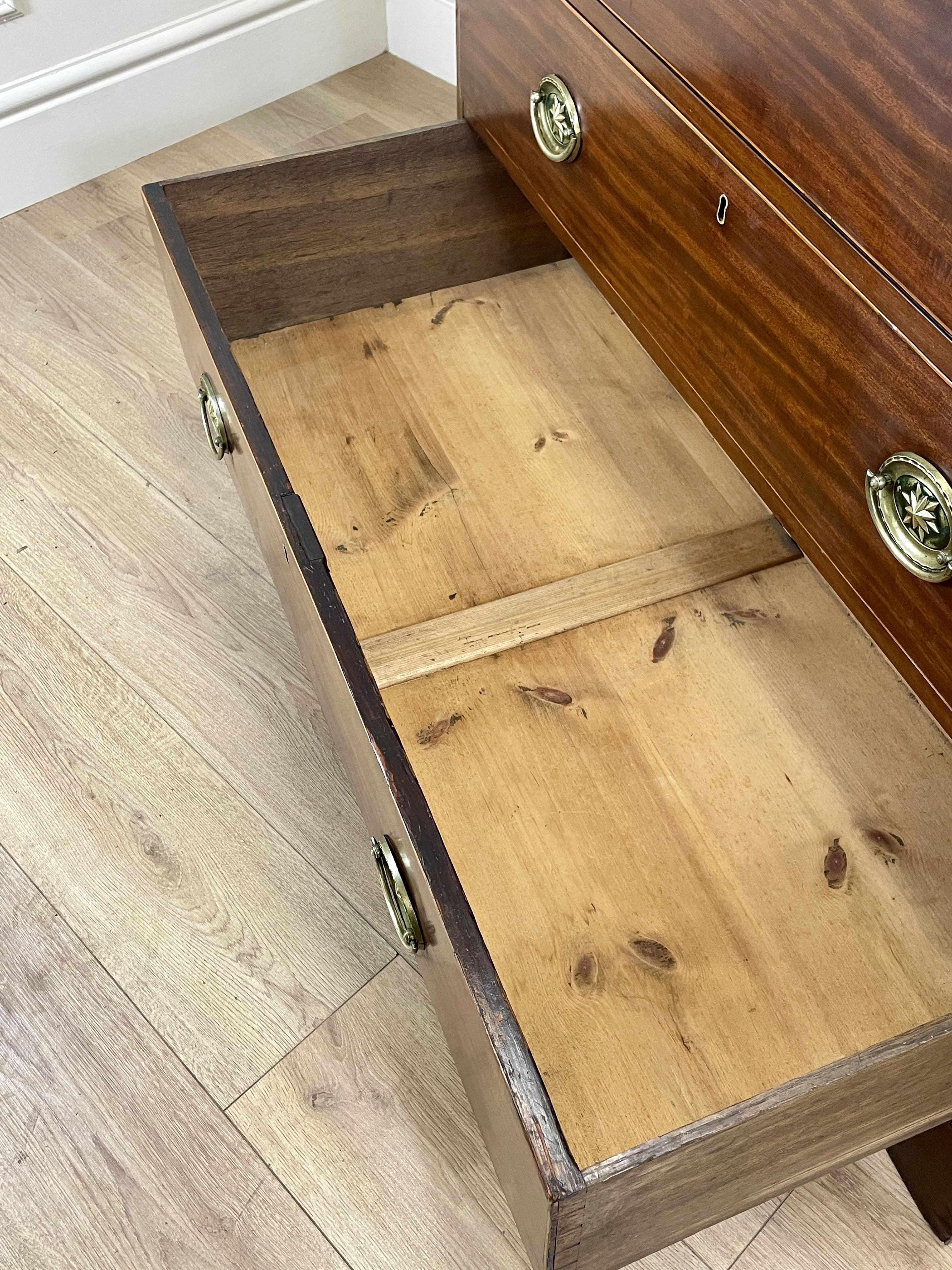 Wooden drawer with brass handles on a wooden floor.