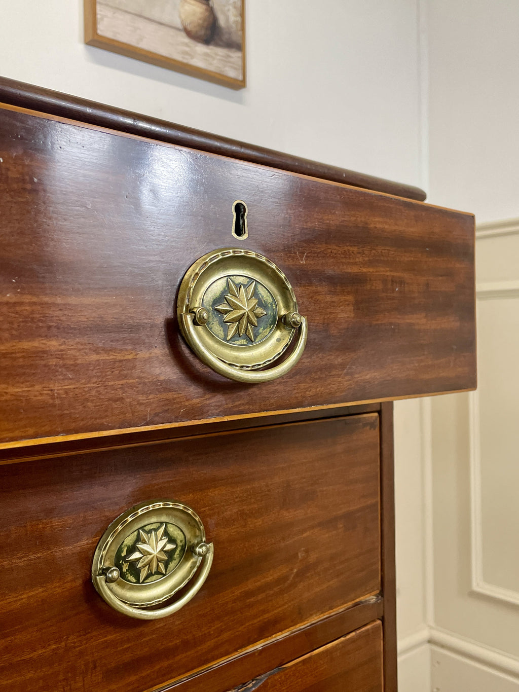 Wooden drawer with brass handles on a white wall background