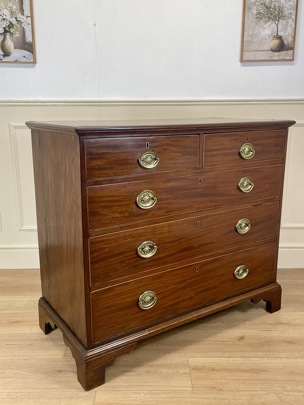 Wooden dresser with brass handles on a wooden floor.