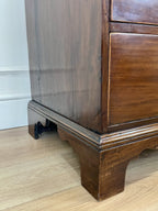 Wooden cabinet with a visible foot on a wooden floor.