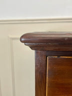 Close-up of a wooden cabinet corner with a neutral wall background