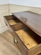 Wooden desk with an open drawer in a room with white walls and wooden floor.