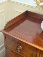 Wooden dresser with a drawer in a room with white walls and decorative elements.