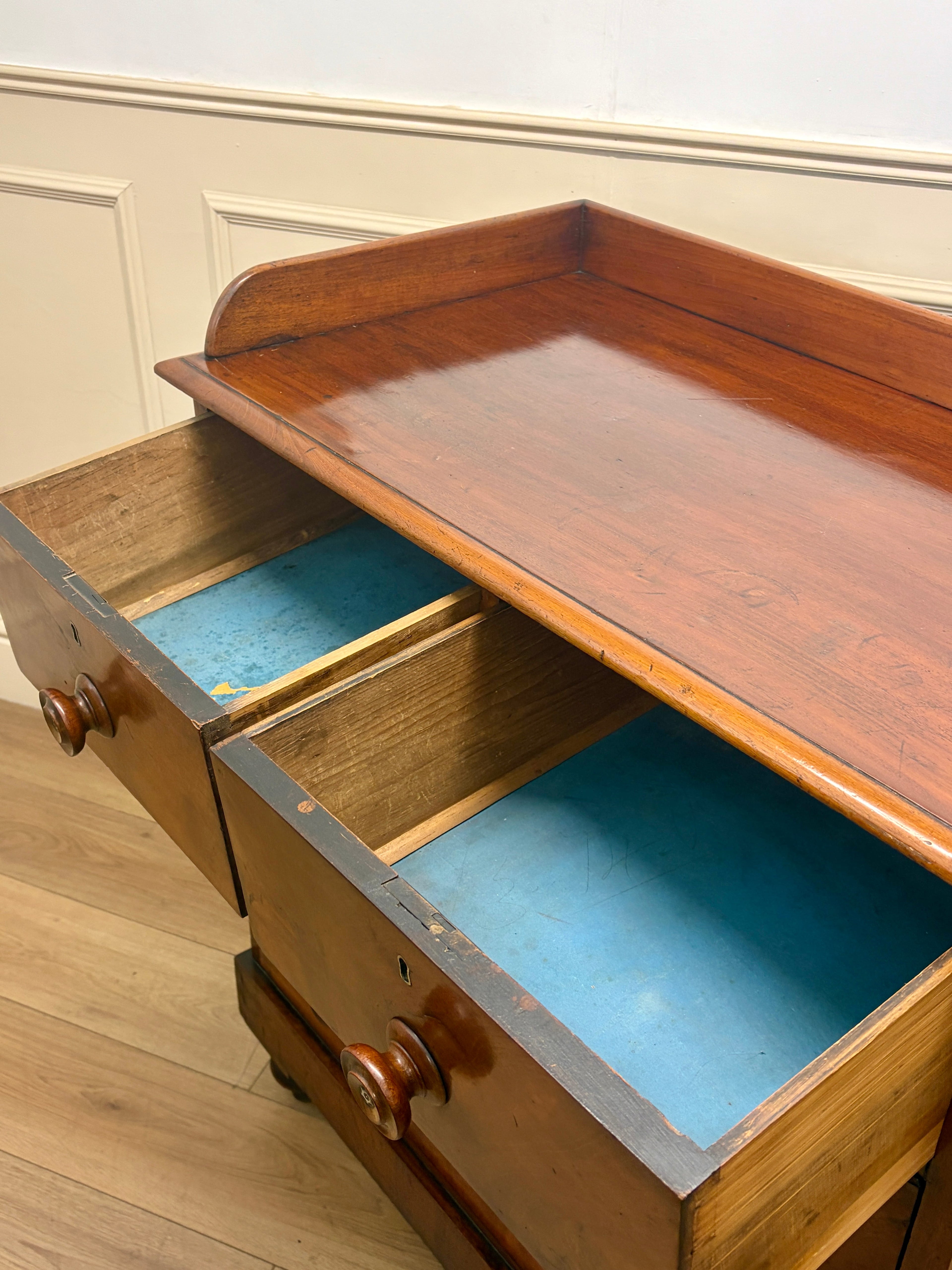 Wooden drawer with open top tray and blue interior on a wooden floor.