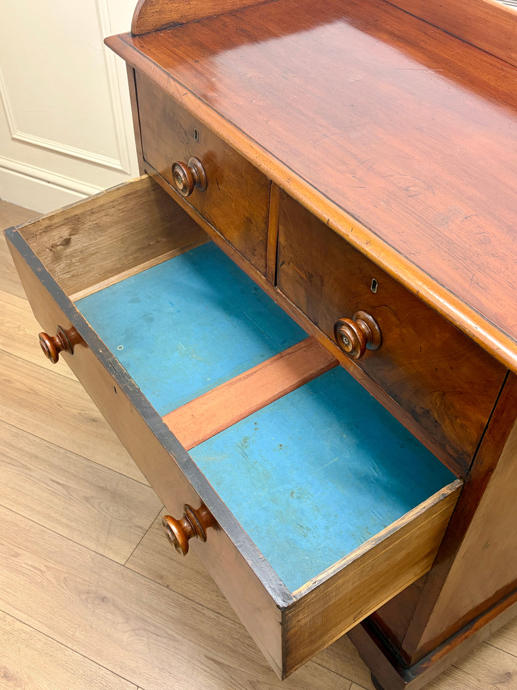 Wooden drawer with a blue interior on a wooden floor.