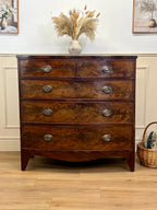 Wooden dresser with four drawers on a wooden floor, decorated with a vase and basket.
