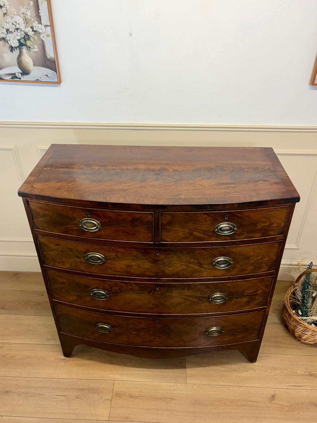 Wooden dresser with curved top and four drawers on a wooden floor.