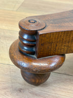 Close-up of a wooden chair leg with intricate design on a wooden floor.
