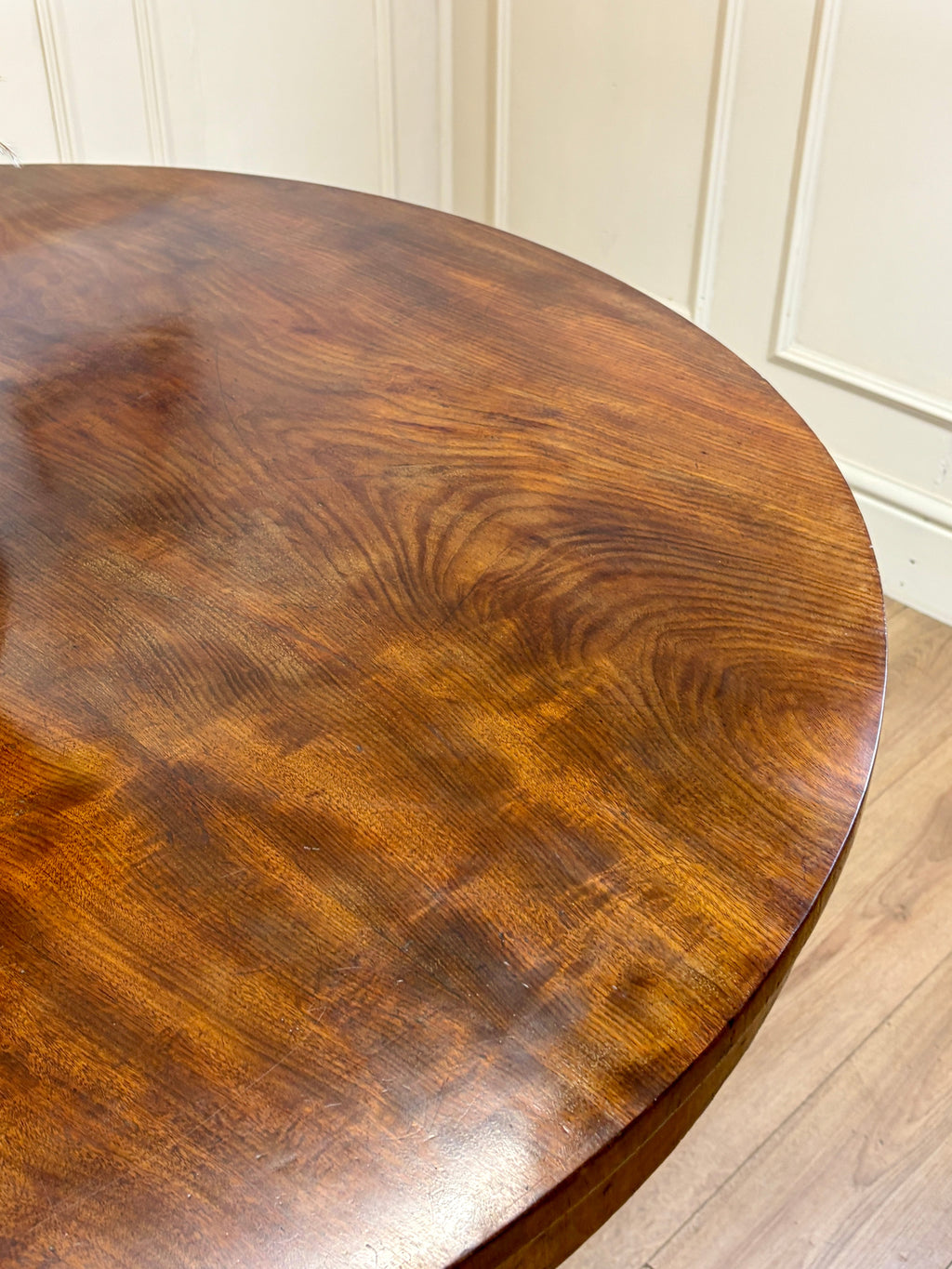 Round wooden table with a dark brown finish against a white paneled wall.