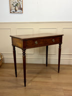 Wooden side table with a single drawer against a white paneled wall.