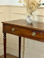 Wooden side table with a vase of dried plants on a neutral wall background