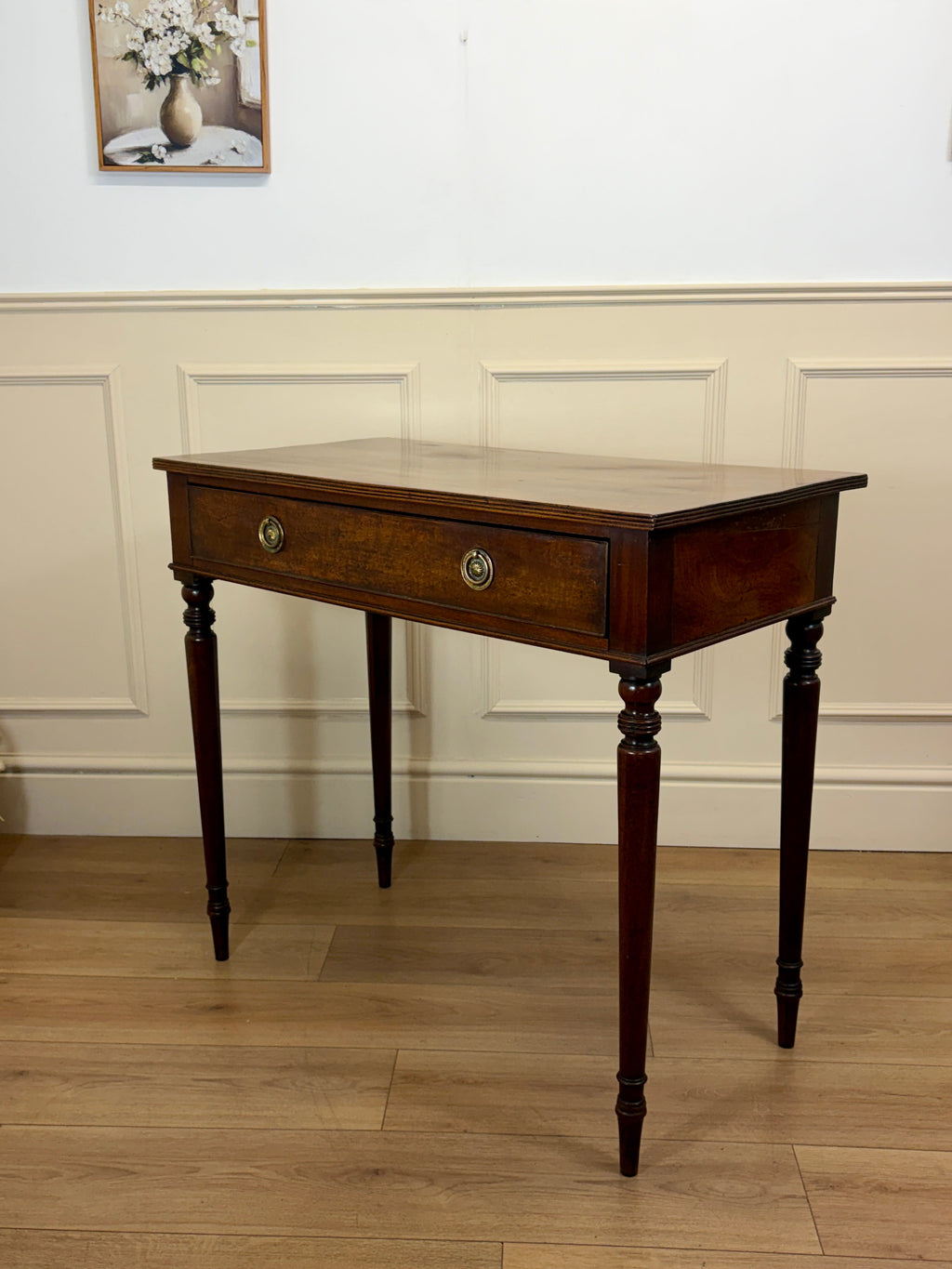 Wooden side table with a drawer against a white wall