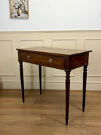 Wooden side table with a drawer against a white wall