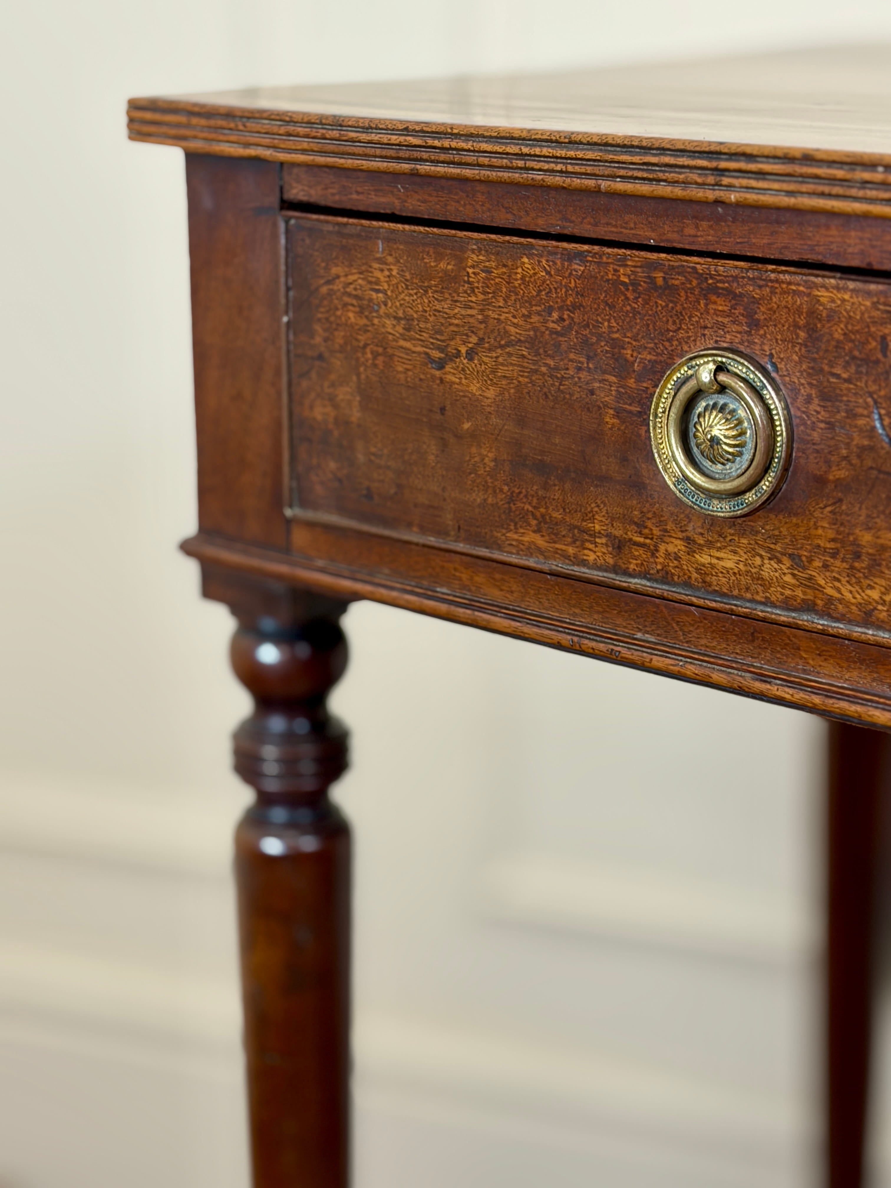 Close-up of a wooden side table with a drawer and brass handle on a beige background