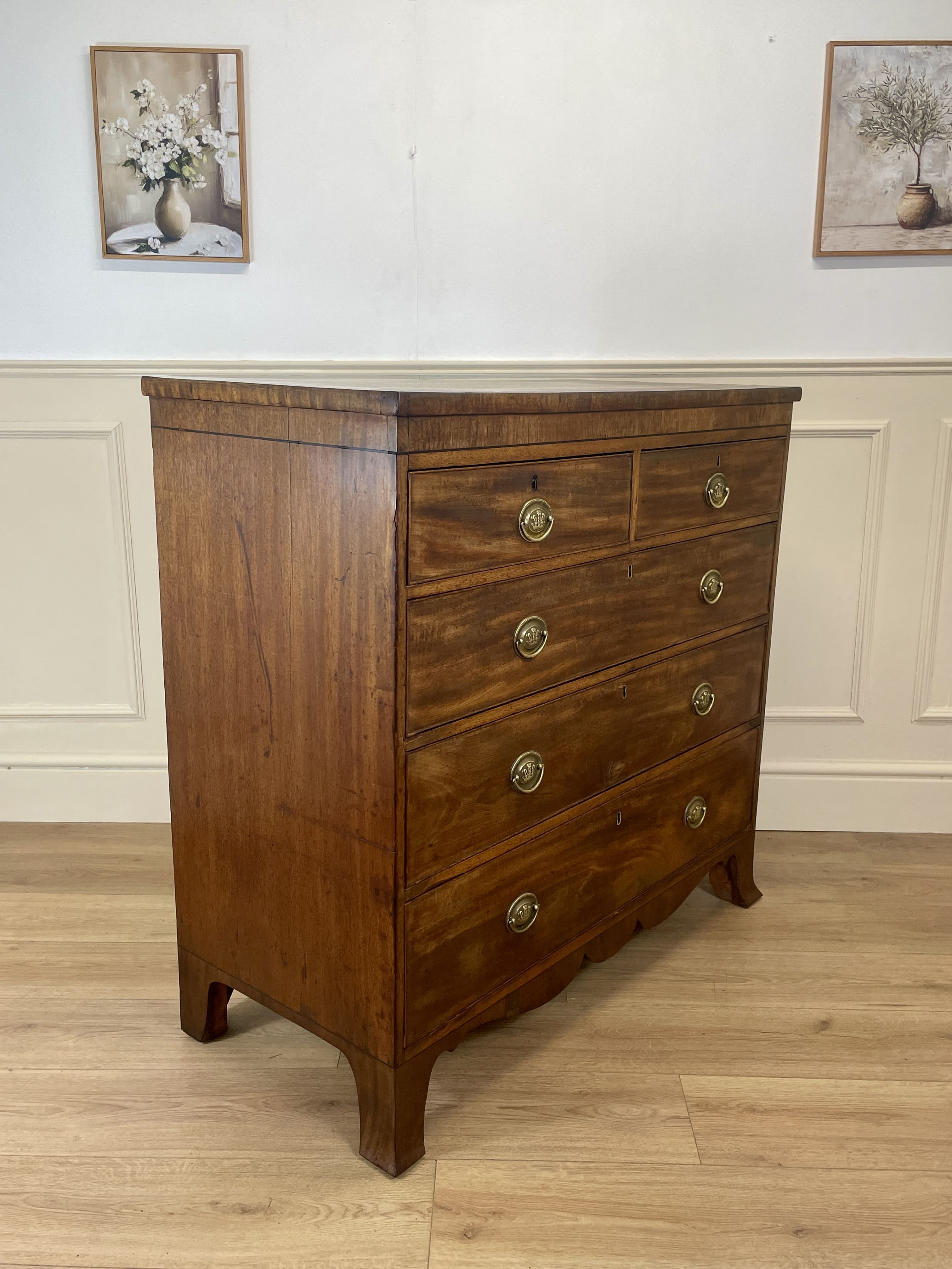 Angled view showing antique mahogany chest of drawers for bedroom with graduated drawers and Prince of Wales brasses
