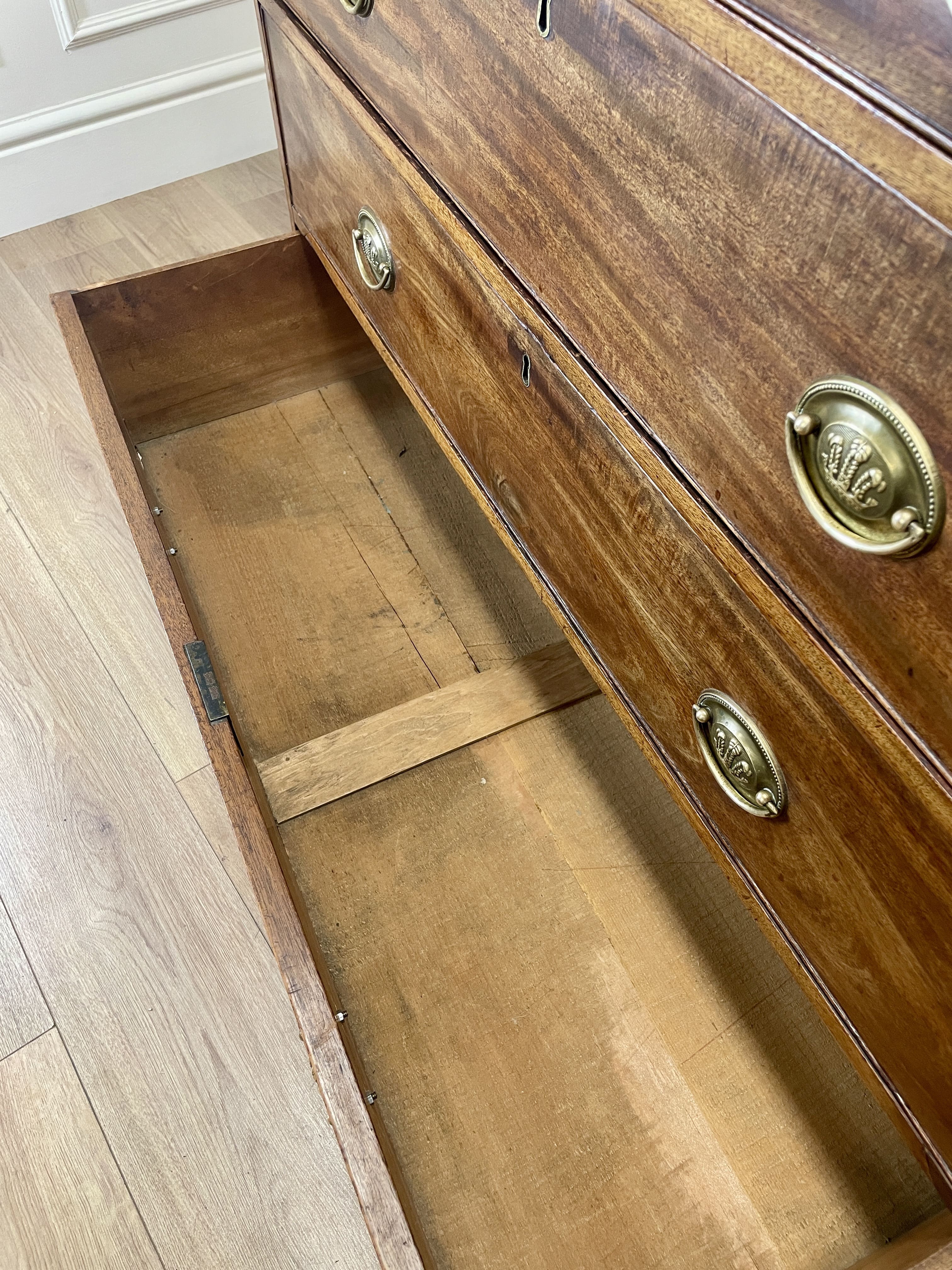 Angled view showing antique mahogany chest of drawers for bedroom with graduated drawers and Prince of Wales brasses