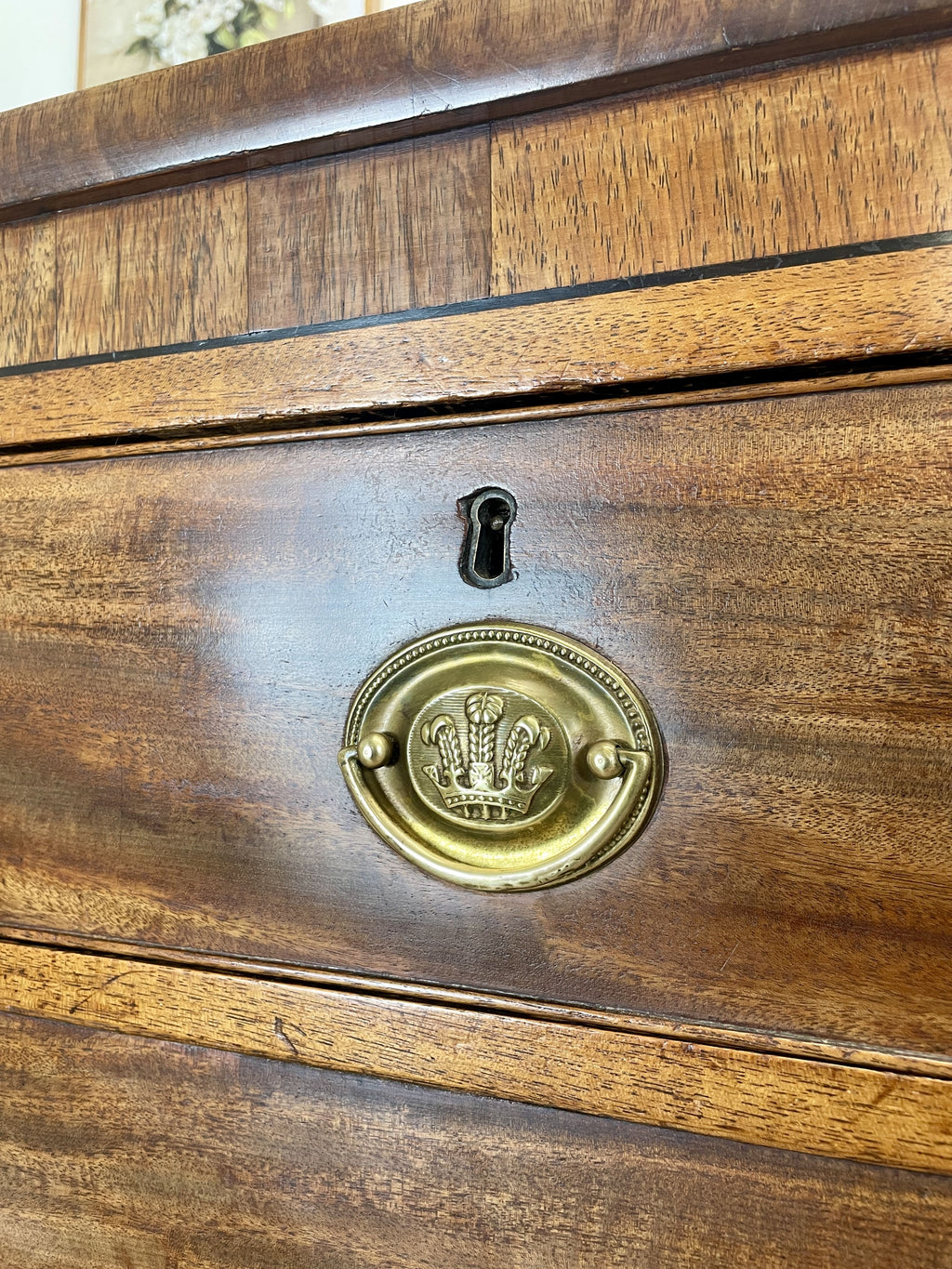 Angled view showing antique mahogany chest of drawers for bedroom with graduated drawers and Prince of Wales brasses