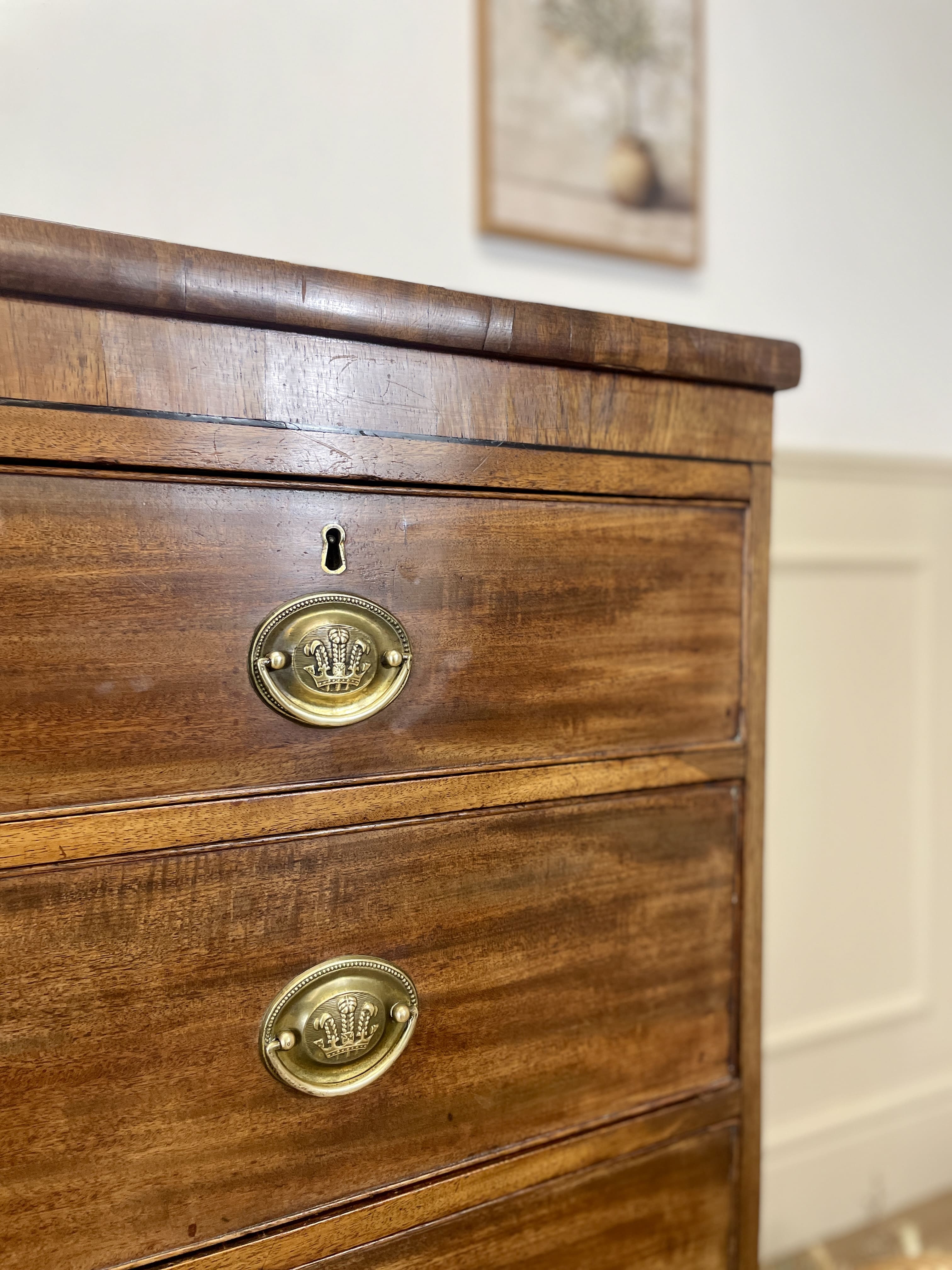 Angled view showing antique mahogany chest of drawers for bedroom with graduated drawers and Prince of Wales brasses