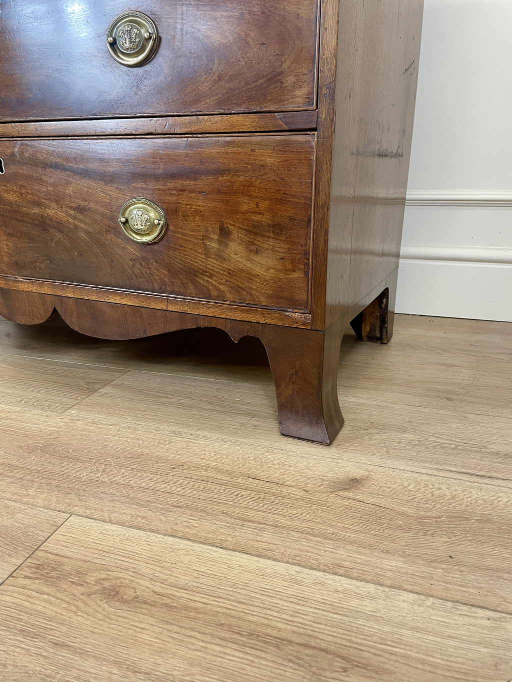 Angled view showing antique mahogany chest of drawers for bedroom with graduated drawers and Prince of Wales brasses