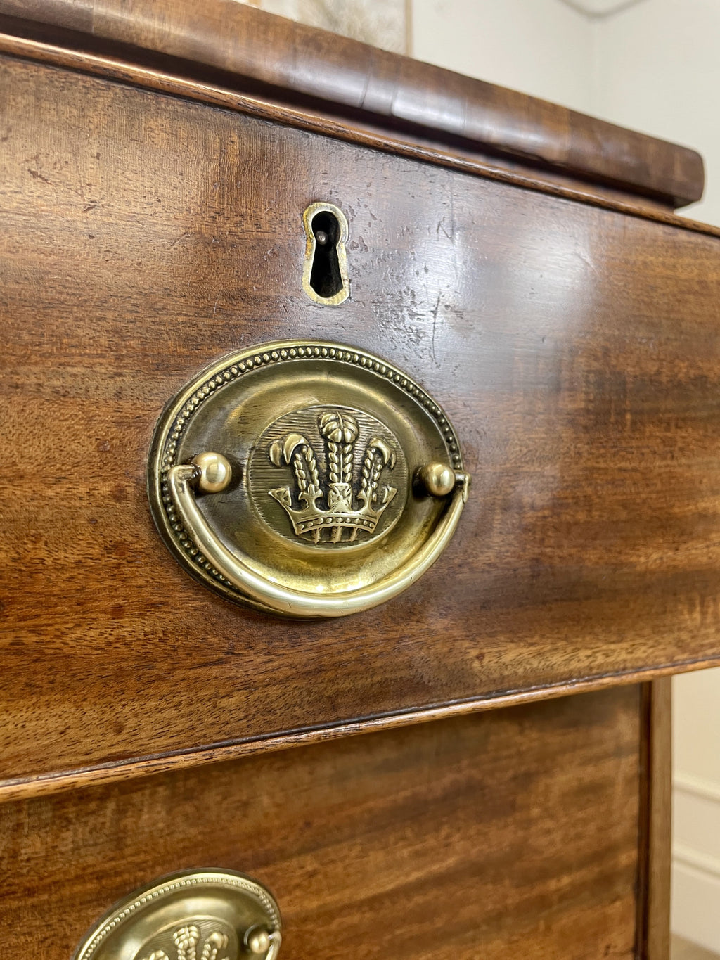 Angled view showing antique mahogany chest of drawers for bedroom with graduated drawers and Prince of Wales brasses