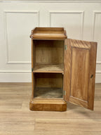 Wooden cabinet with open door on a wooden floor against a white paneled wall.