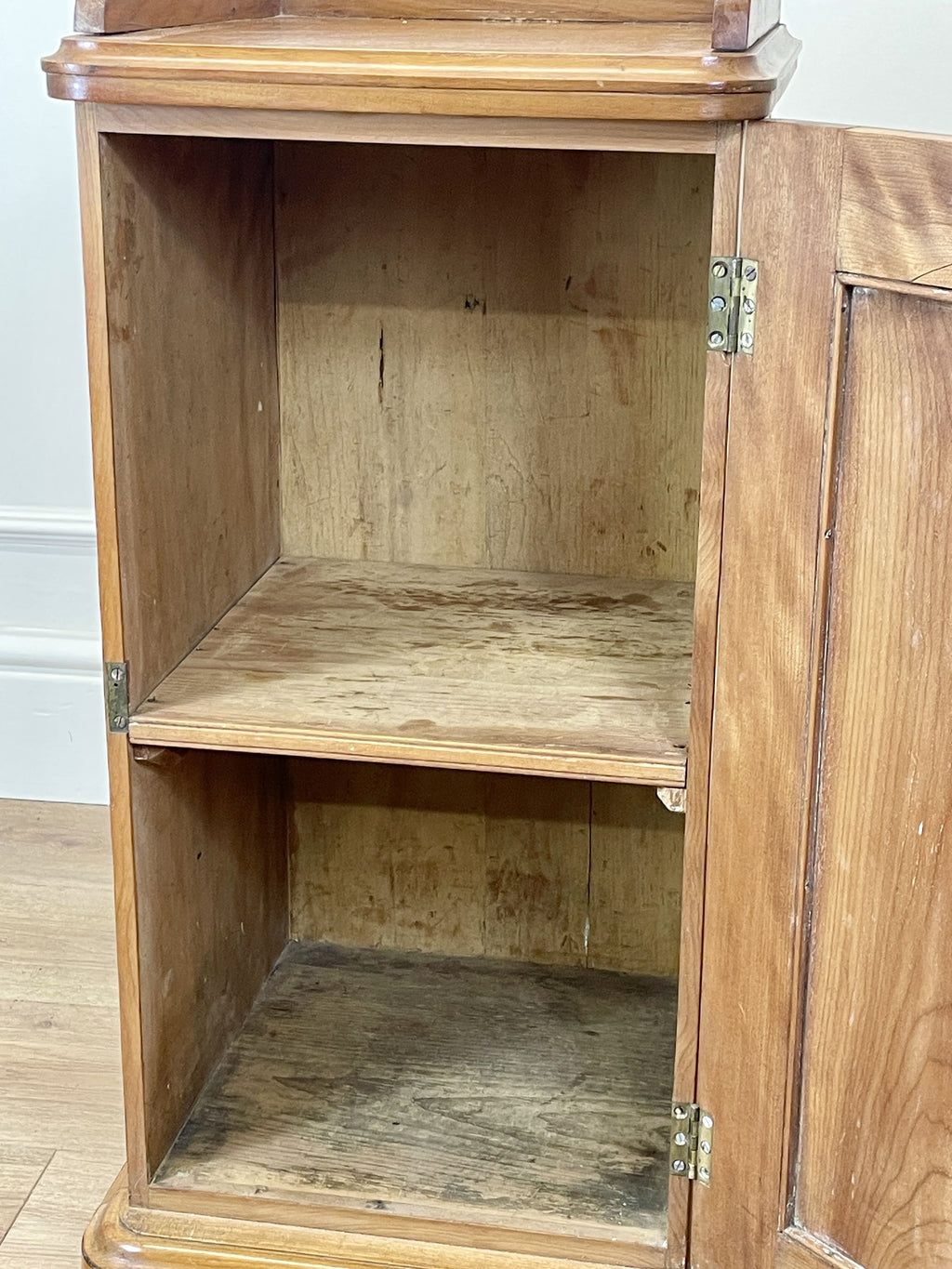 Wooden cabinet with open doors on a wooden floor.