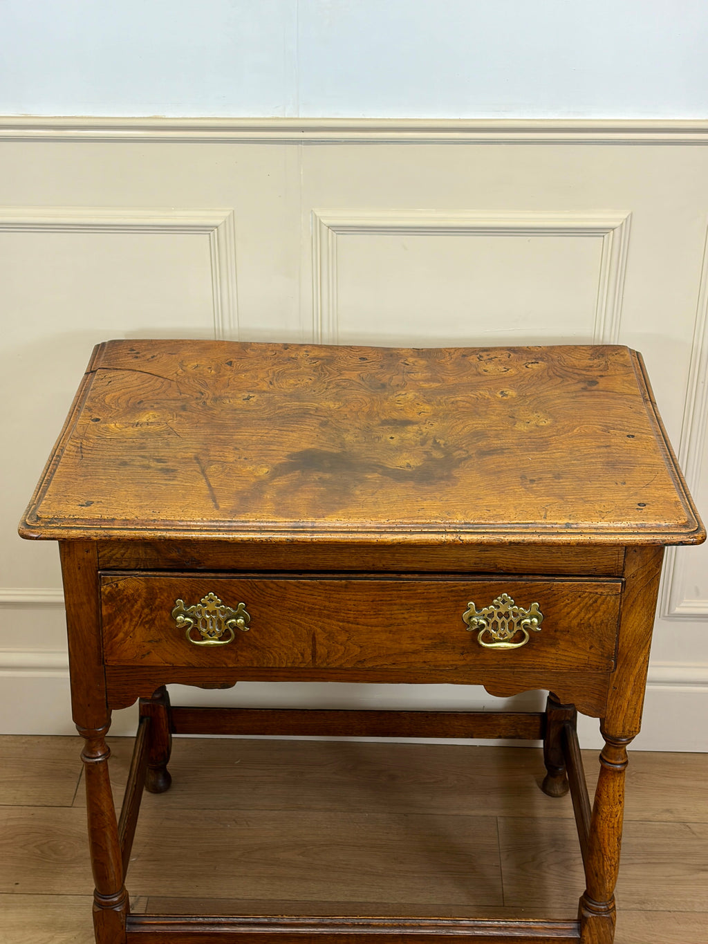 Wooden side table with a drawer against a light-colored wall.