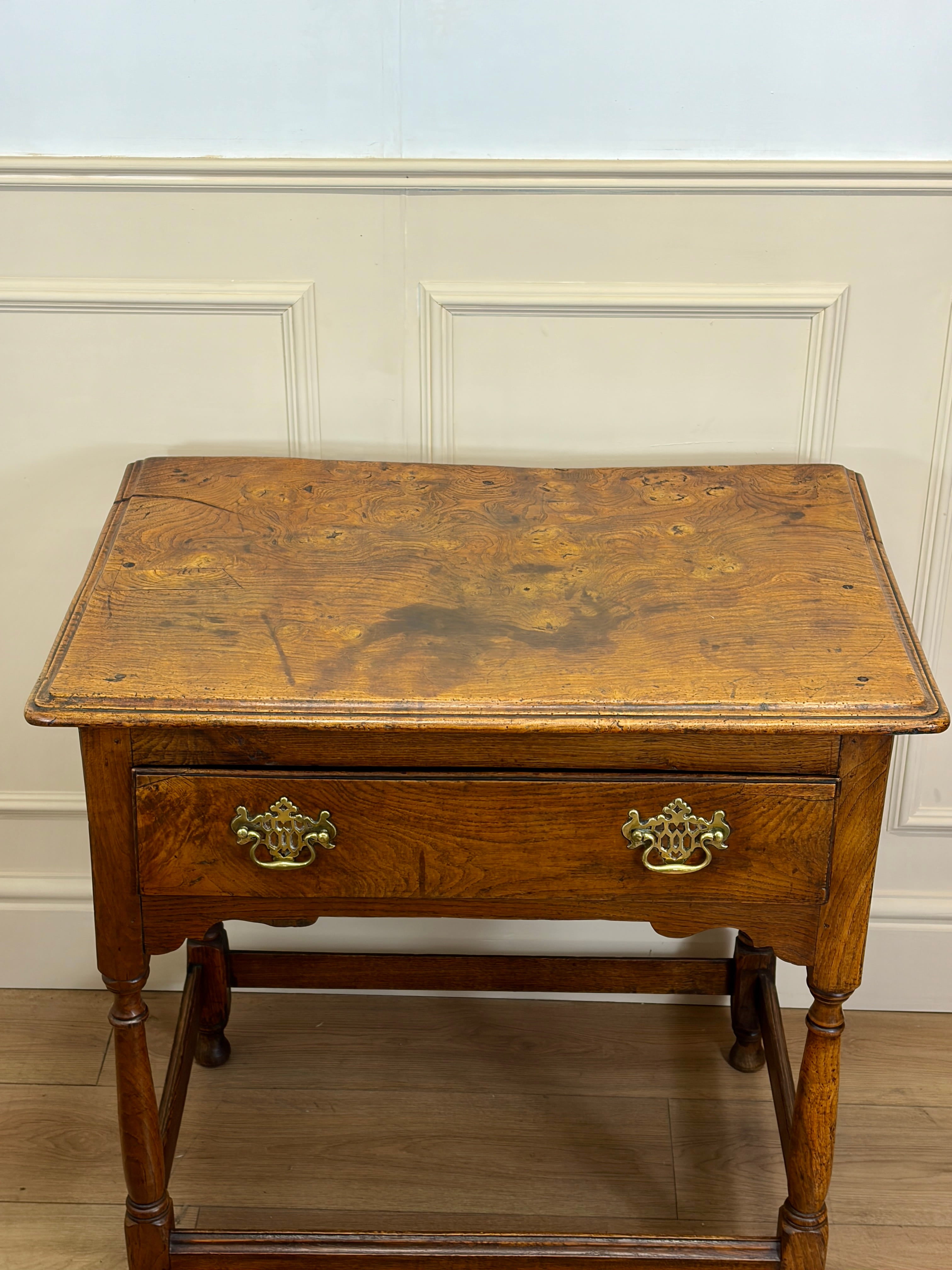 Wooden side table with a drawer against a light-colored wall.