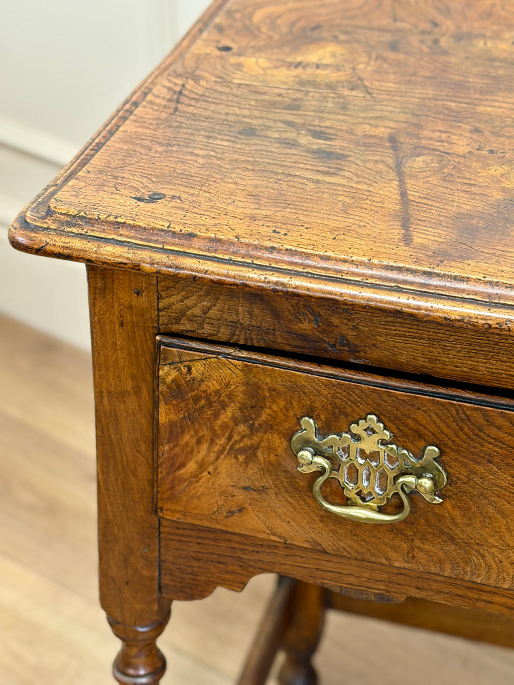 Wooden drawer with a brass handle on a wooden floor.