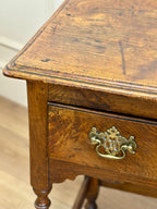 Wooden drawer with a brass handle on a wooden floor.