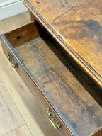 Wooden drawer with brass handles on a wooden floor.